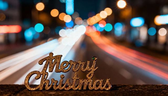 Golden merry christmas sign on concrete ledge with light trails and urban bokeh night glow