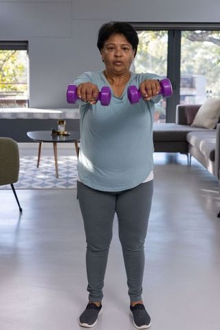Senior indian woman exercising with dumbbells at home