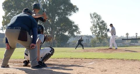 Pitcher preparing to throw while batter waiting and catcher crouching at home plate