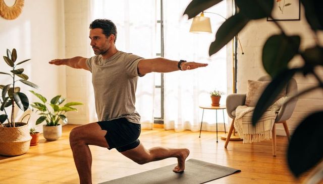 Man practicing forward lunge workout in sunlit cozy living room with indoor plants