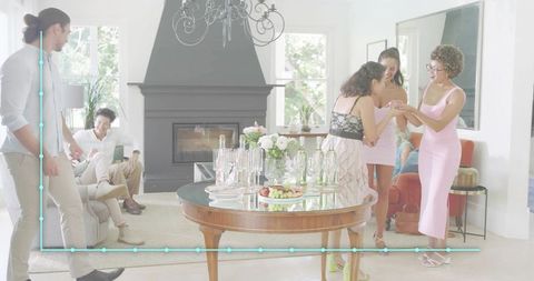 Women Chatting in Bright Living Room During Casual Party Around Table with Drinks and Snacks