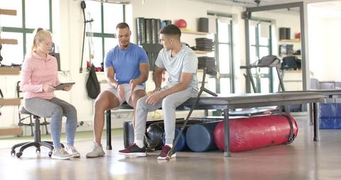 Physical Therapist Guiding Clients in Rehabilitation Session at Gym
