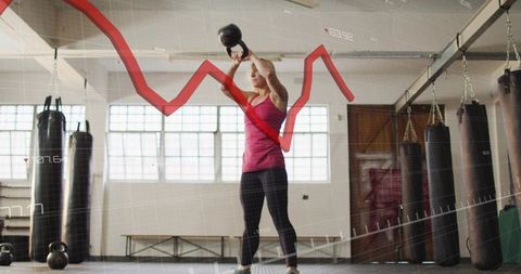 Female Athlete Raising Kettlebell Overhead in Gym with Performance Graph Overlay