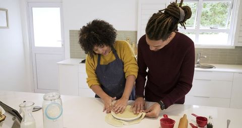 Couple preparing homemade pie dough together on kitchen island in modern home
