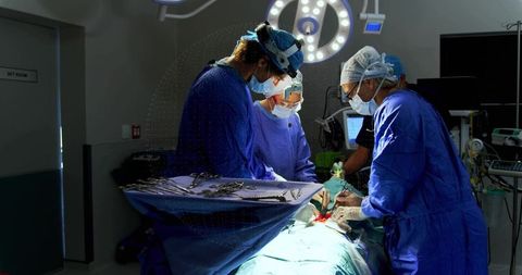 Surgical team performing complex abdominal surgery in sterile operating room under lights