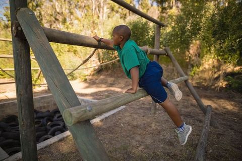 Energetic boy climbing wooden adventure obstacle outdoors
