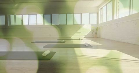 Sunlit minimalist yoga studio featuring dark mats and rolled towels