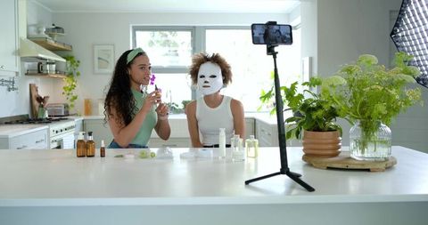 African beauty creators filming skincare tutorial at bright kitchen island with smartphone