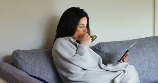 Woman Relaxing on Couch Drinking Tea and Reading Tablet - Download Free Stock Images Pikwizard.com