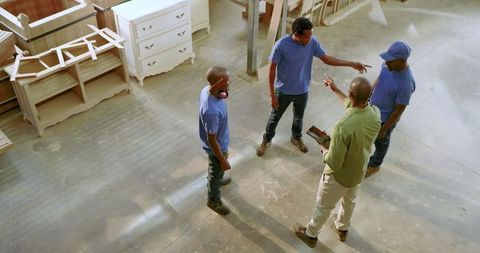 Team of Craftspersons Discussing Plans in a Woodworking Workshop