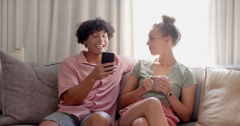 Couple Relaxing on Sofa Sharing Smartphone Moments at Home