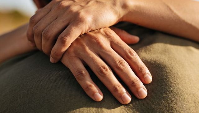 Warm hands resting on partner's back during golden hour expressing tenderness and support