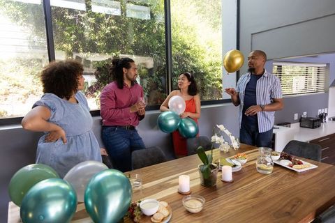 Diverse group celebrating at modern dining room table with balloons
