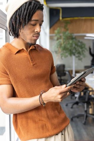 African american man using tablet in modern open-plan coworking space with natural light