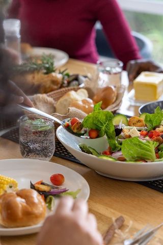Diverse friends sharing family-style meal at sunlit wooden table