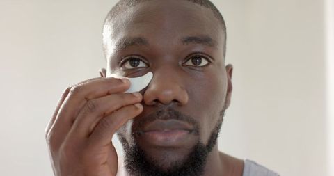 man practicing self-care applying undereye patch - Download Free Stock Images Pikwizard.com