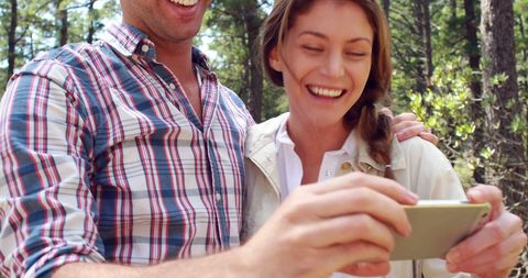 Happy Couple Enjoying Smartphone in Forest Moments