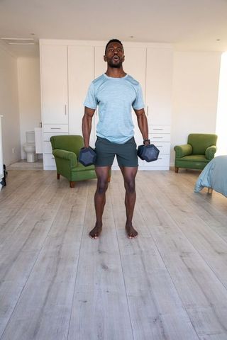 Man Exercising with Dumbbells in Bedroom for Home Workout Routine