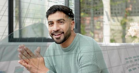 Smiling man sitting on sofa presenting financial charts with overlaid graphs and data visualization