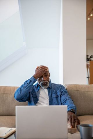 Senior man in thought while viewing laptop in cozy home