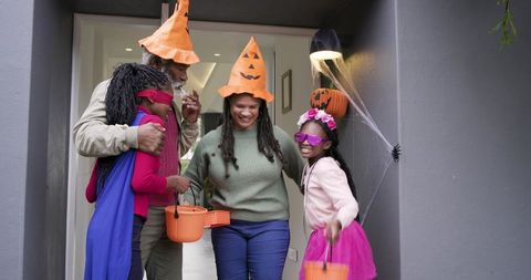 Diverse Family Celebrating Halloween Doorstep Wearing Costumes Trick-or-Treat Buckets