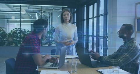 Female team leader presenting to colleagues during strategy meeting in modern boardroom