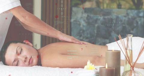 Relaxing spa back massage receiving aromatherapy treatment with candles and diffuser