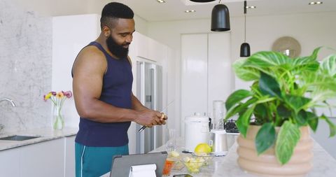 Man Slicing Pineapple in Modern Kitchen with Green Foliage