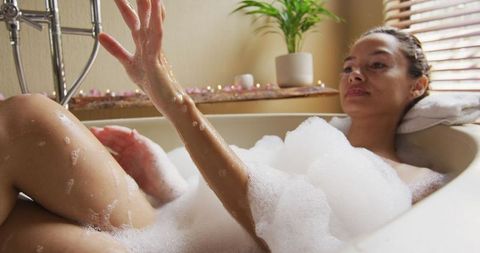 Relaxed woman enjoying a luxurious foam bath, indulging in self-care