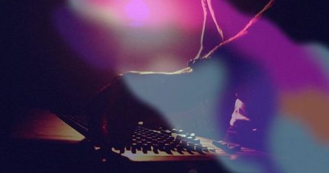 Mysterious Coder at Laptop with Vibrant Lights in Dark Room