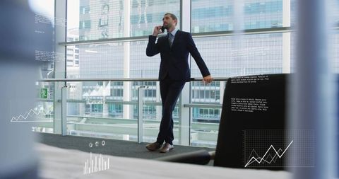 Confident executive talking on smartphone while overlooking skyline from modern office