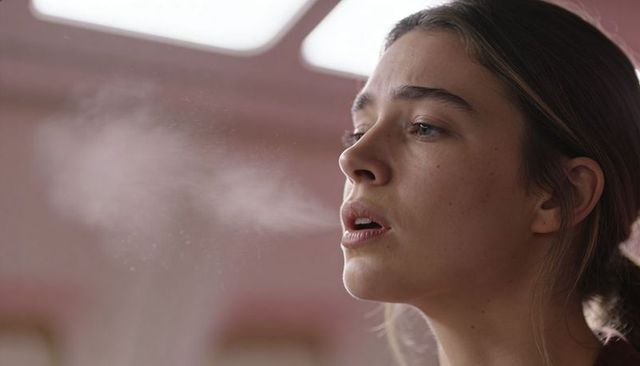 Young woman exhaling visible breath in soft skylight portrait for wellness and breathwork