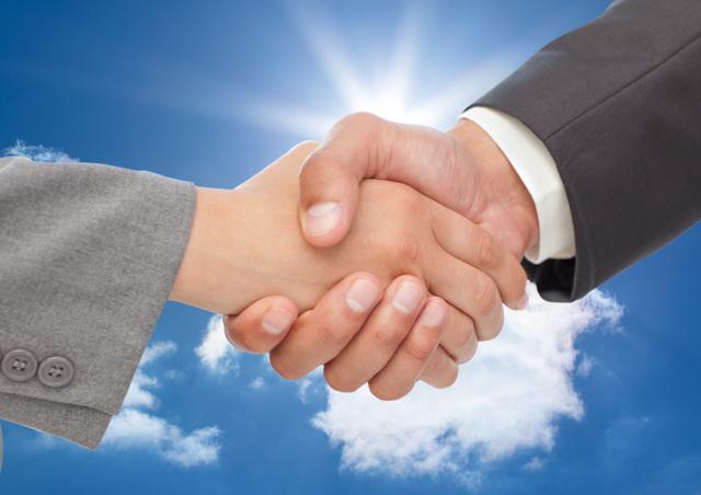 Business executives shaking hands against a bright blue sky with clouds, symbolizing successful partnership and collaboration. Ideal for use in business presentations, websites, and marketing materials to convey themes of trust, cooperation, and professional success.