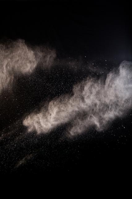 Dust powder creating dramatic feel against dark backdrop, ideal for use in creative projects such as digital art, backgrounds for presentations, science illustrations, and advertisements highlighting clarity and cleanliness themes.