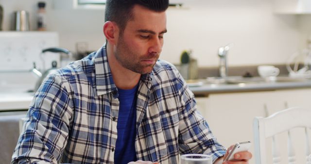 Man in Plaid Shirt Using Smartphone at Kitchen Table - Download Free Stock Images Pikwizard.com