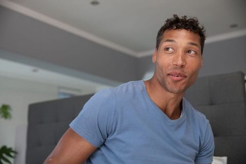 Mid adult man relaxing on gray tufted sofa in modern living room