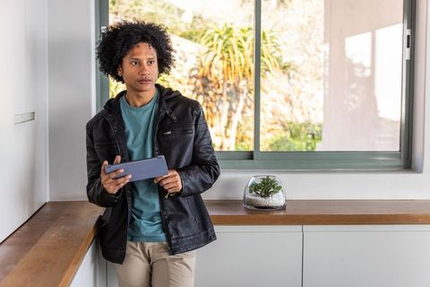 African American man leaning on counter holding tablet in contemporary minimalist interior