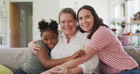 Happy Couple Embracing Daughter on a Cozy Sofa