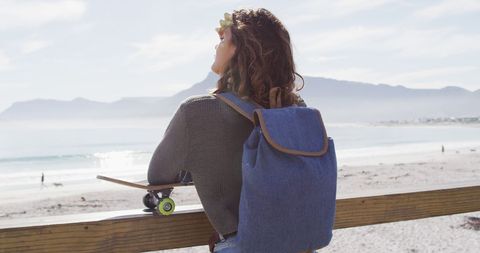Young Woman with Skateboard Enjoying Sea View