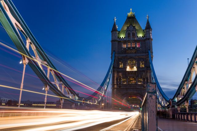 London's Tower Bridge is beautifully illuminated at night with light trails from passing traffic. Ideal for travel websites, English culture blogs, architecture magazines, and cityscape presentations highlighting London's historic landmarks.