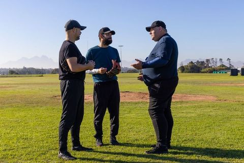 Baseball coach briefing two players on mound strategy during sunny practice session