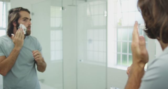 Caucasian man applying shaving cream while looking in the mirror at home - Download Free Stock Photos Pikwizard.com