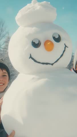 Kids Steadying Snowman While Camera Zooming to Reveal Carrot Nose in Vertical Winter Clip