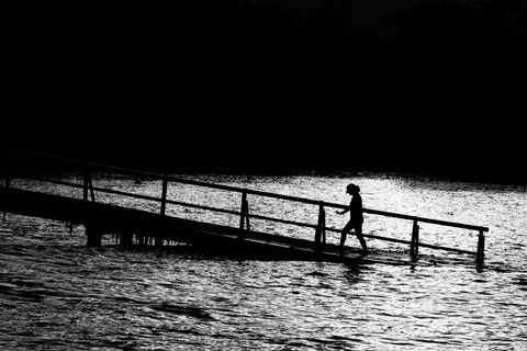 Silhouette of Man Walking on Pier During Twilight