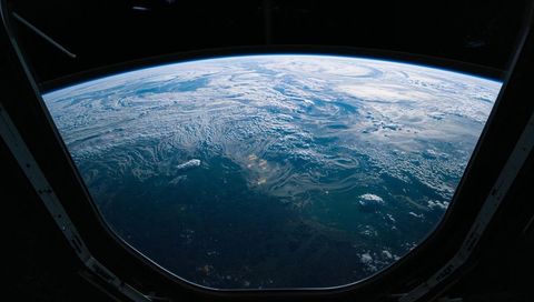 Framing earth from cupola window, revealing atmospheric limb, cloud swirls, ocean bands