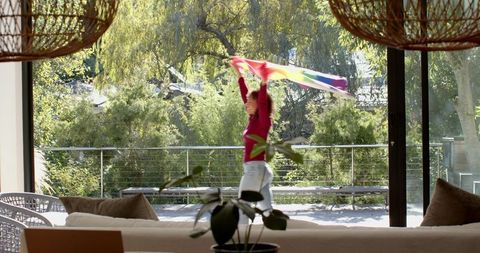 Young Woman Joyfully Waving Colorful Flag on Sunny Terrace