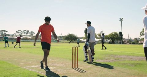 Asian cricketer appealing at stumps during amateur team match on sunny green pitch