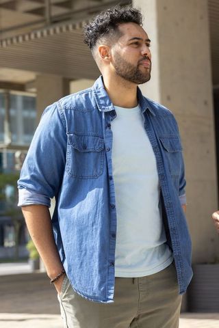 Confident african american man standing outside modern urban building wearing denim shirt