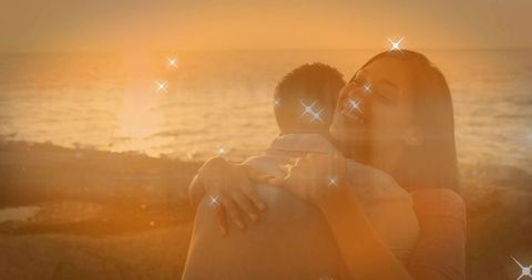 Romantic Sunset Hug with Sparkle Effects on Rocky Shore