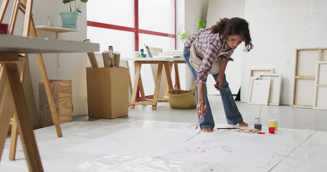 Image of biracial female artist painting on floor in studio - Download Free Stock Photos Pikwizard.com